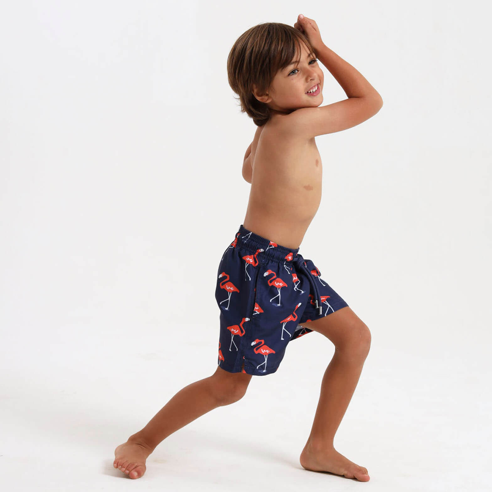 Kid wearing navy swim shorts with an all over flamingo design.