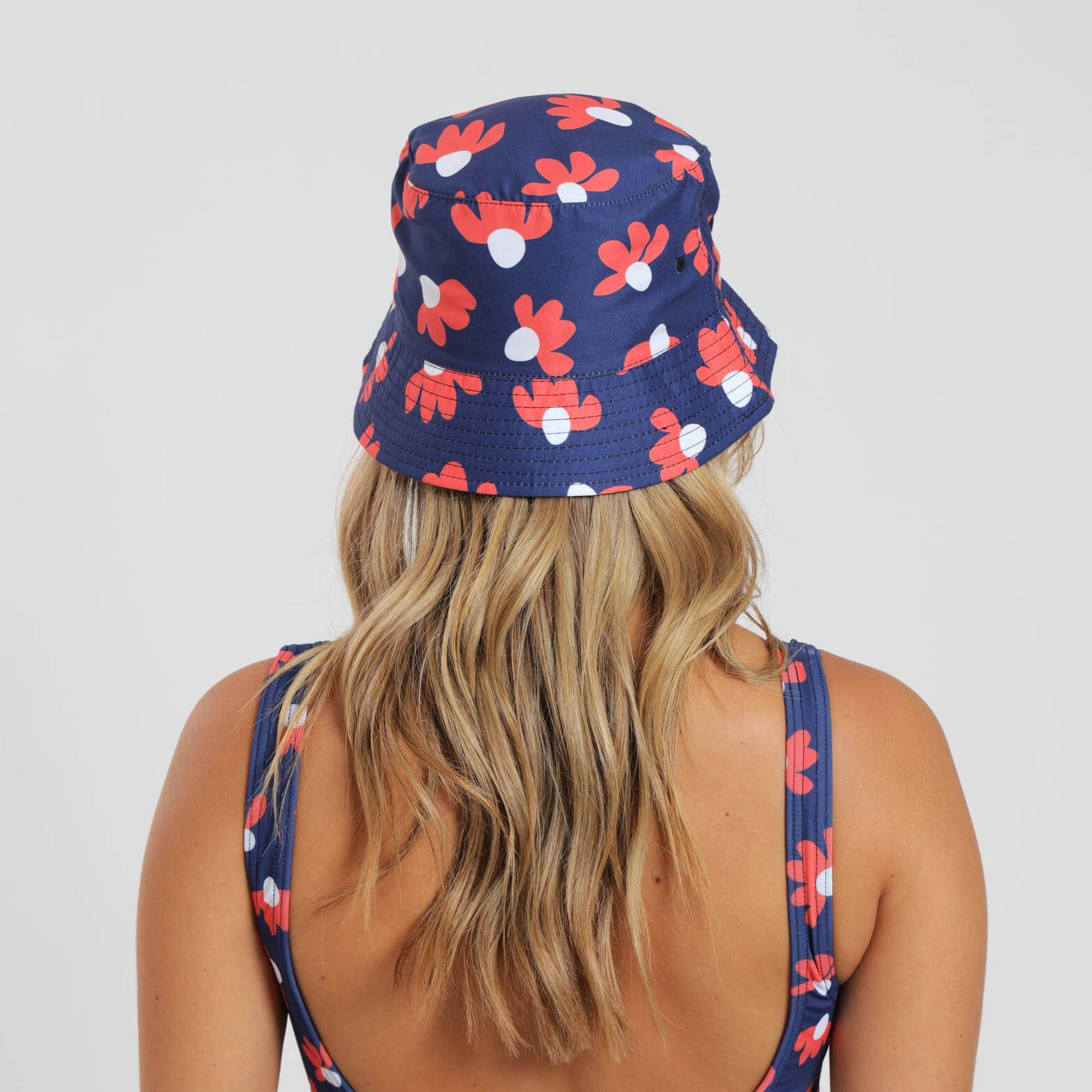 Female wearing a navy bucket hat with a daisy design on it.