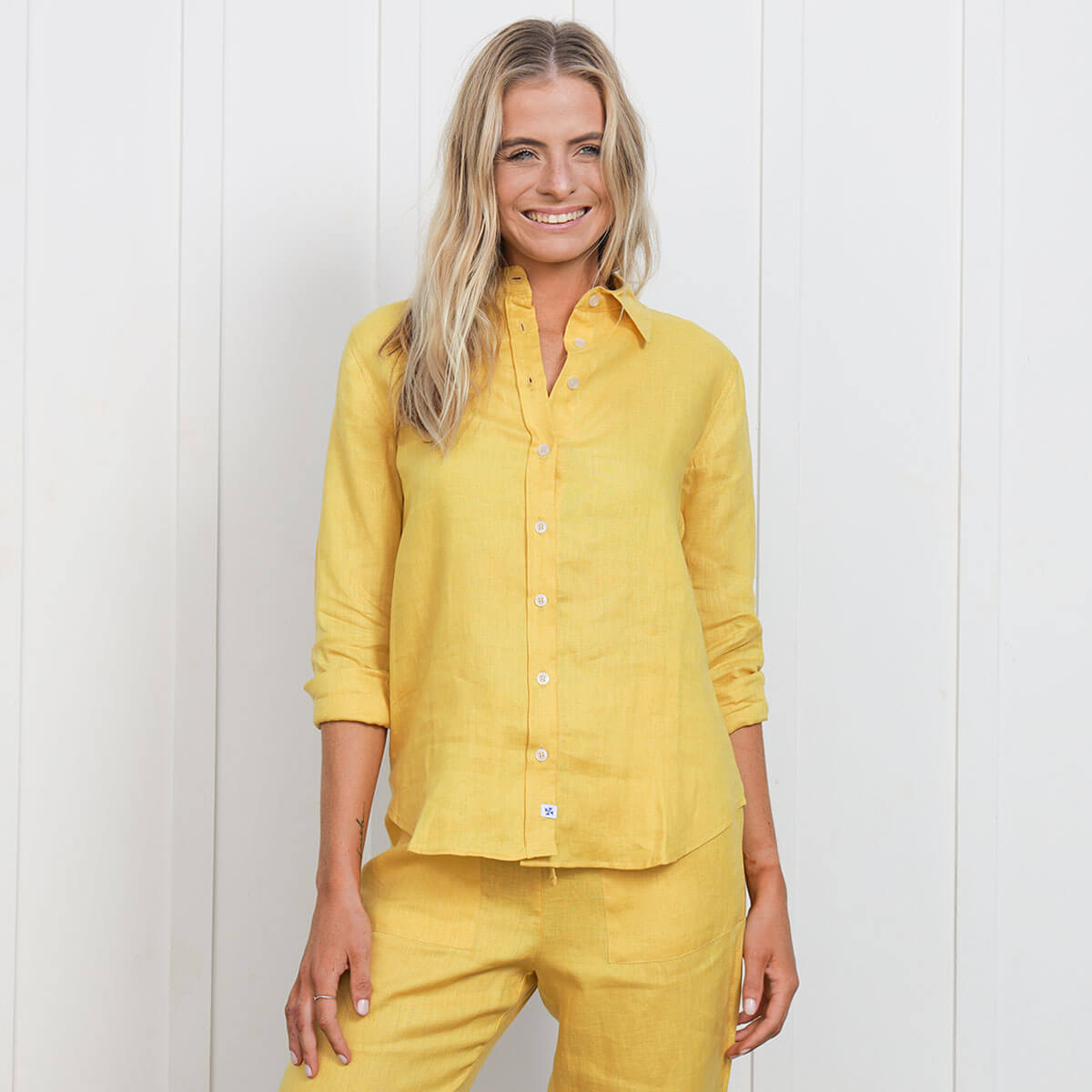 A mustard coloured 100% pure linen shirt being worn with matching pants by a female model.