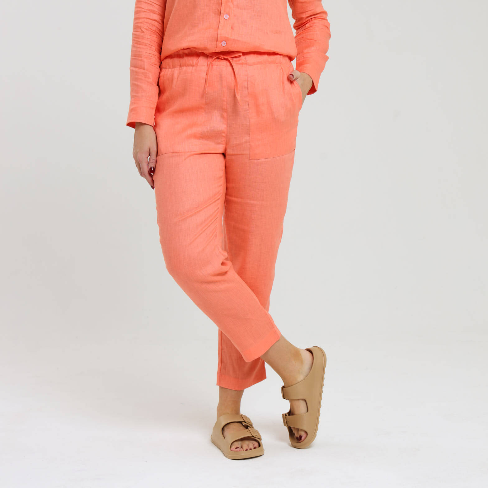 Long peach orange linen pants being worn by a female model.
