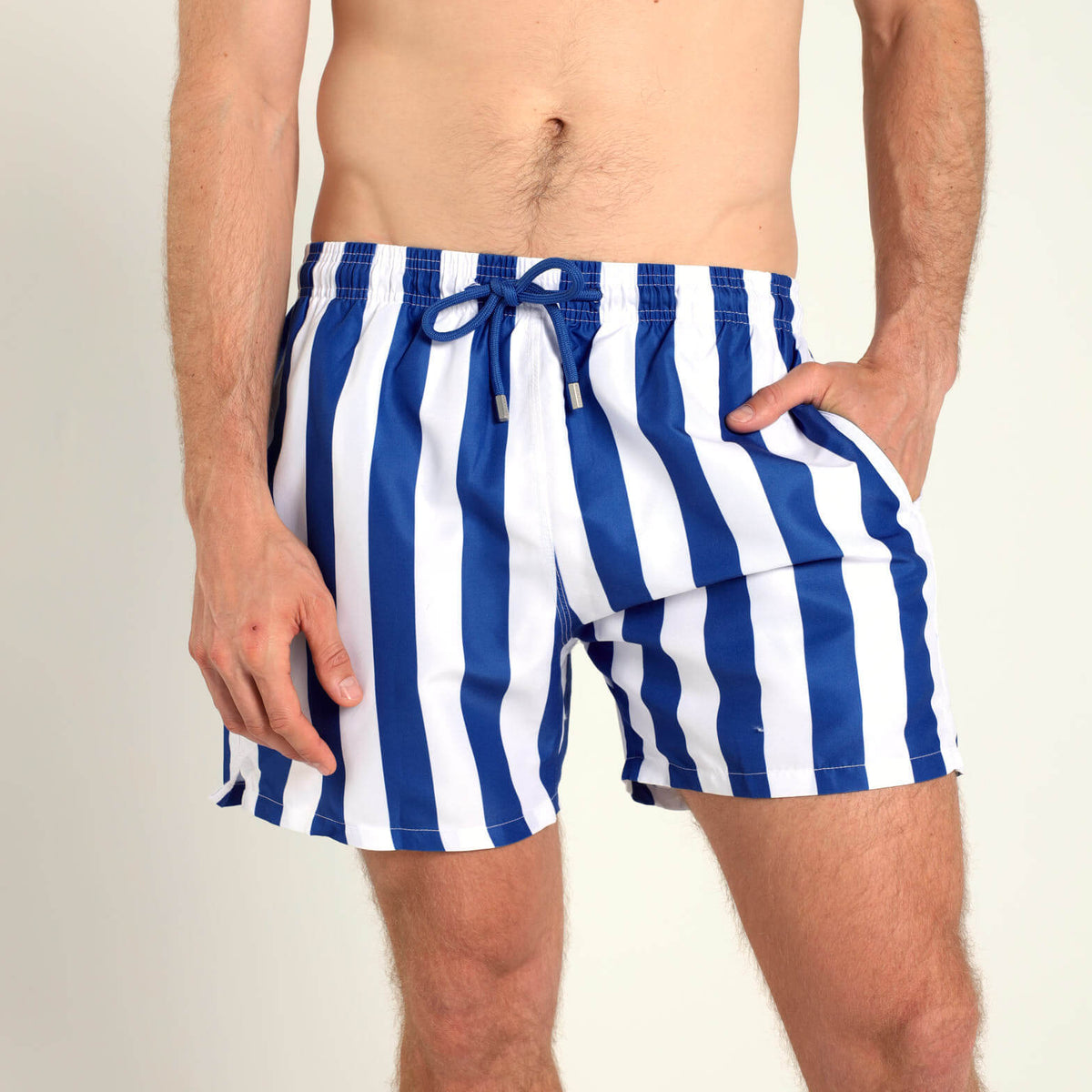 A man wearing Breazies blue and white vertically striped swim trunks, shown from the waist down against a plain light background.