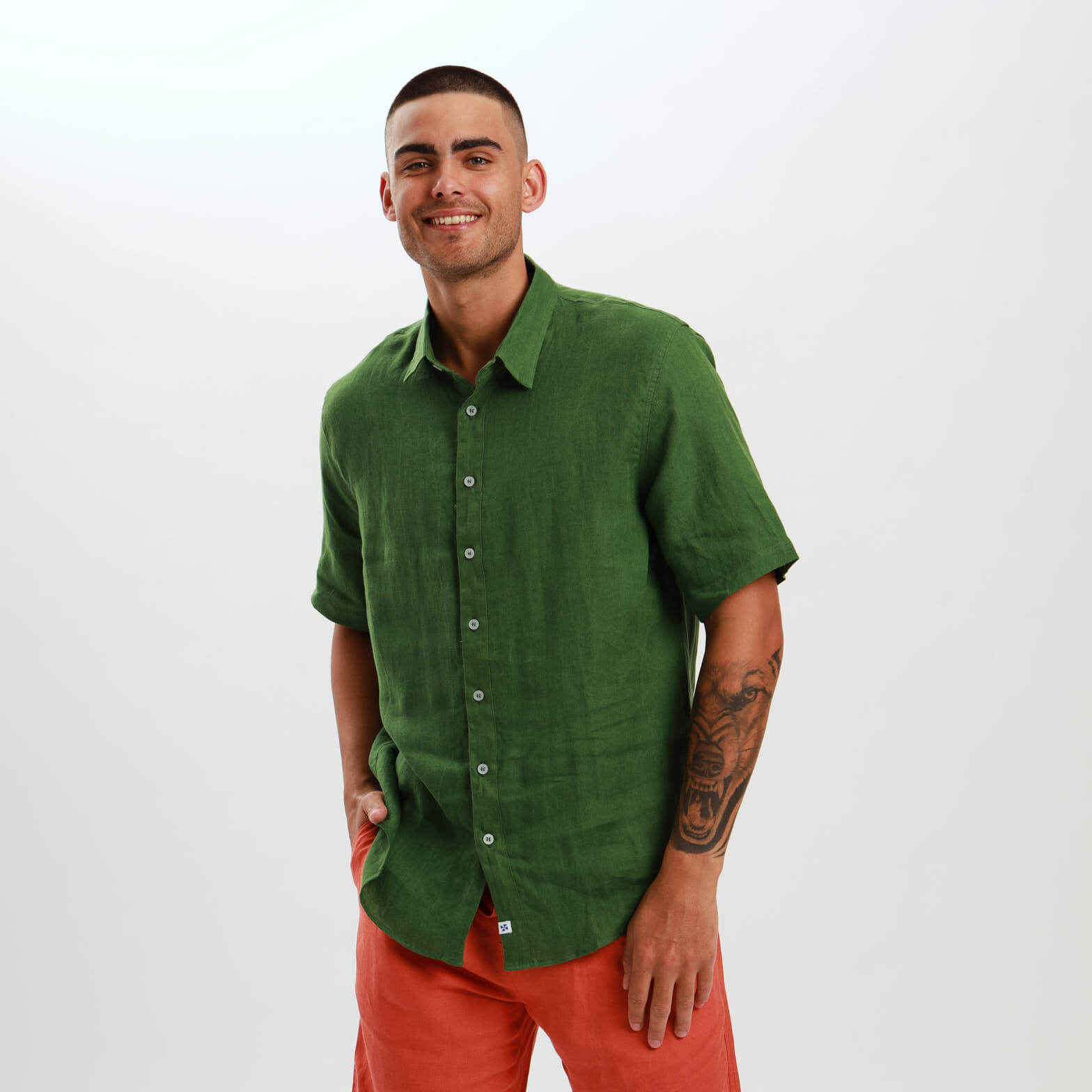 A man wearing a short sleeve olive green linen shirt with a classic collar and front buttons.