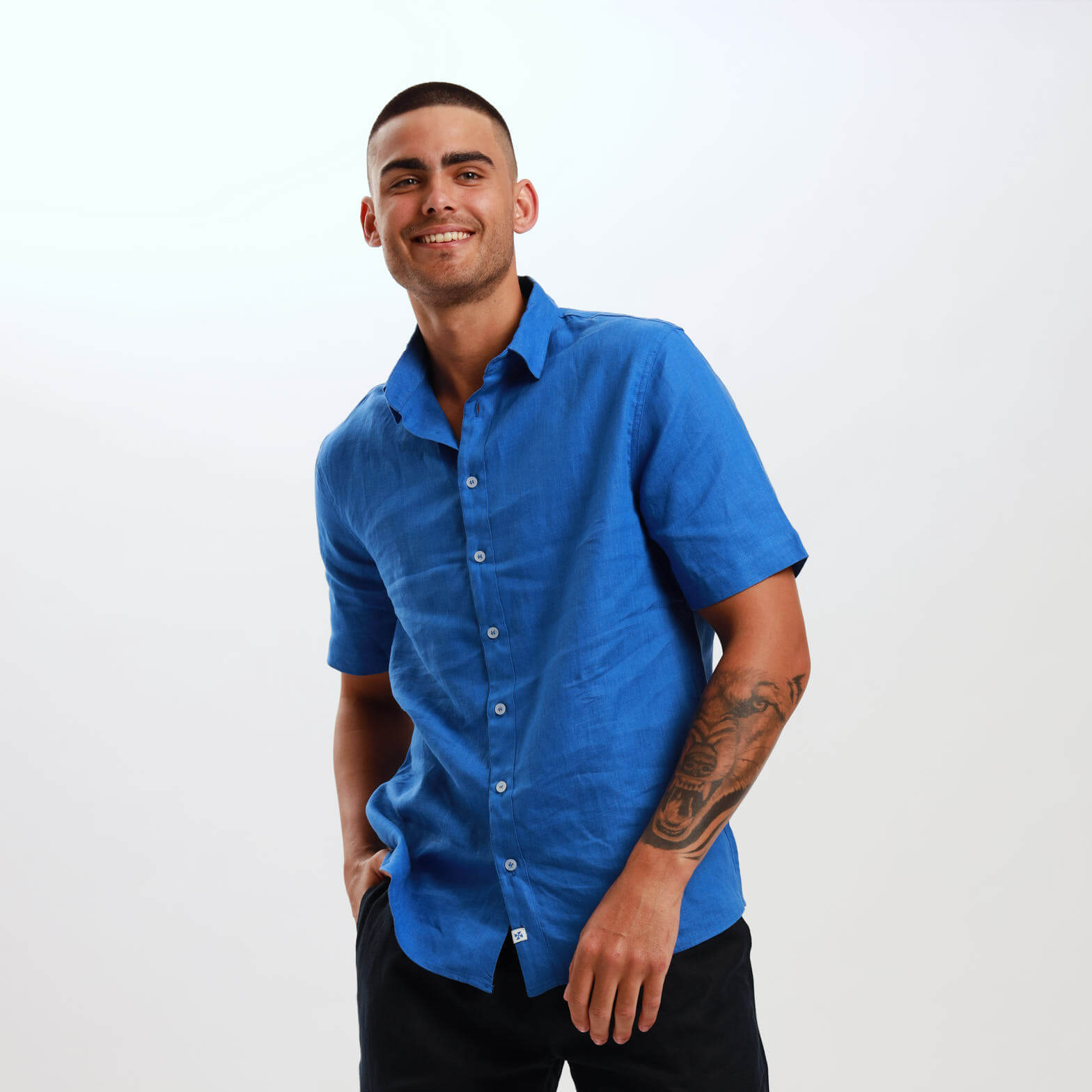 A man wearing a royal blue, short sleeve linen shirt with embossed trims.