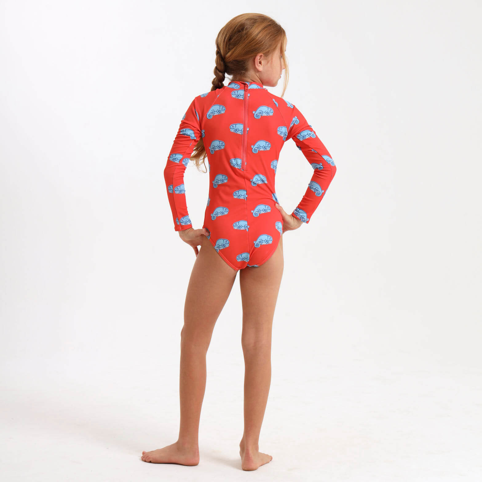 Young girl wearing a long sleeve swimming costume with an orange and blue chameleon print.