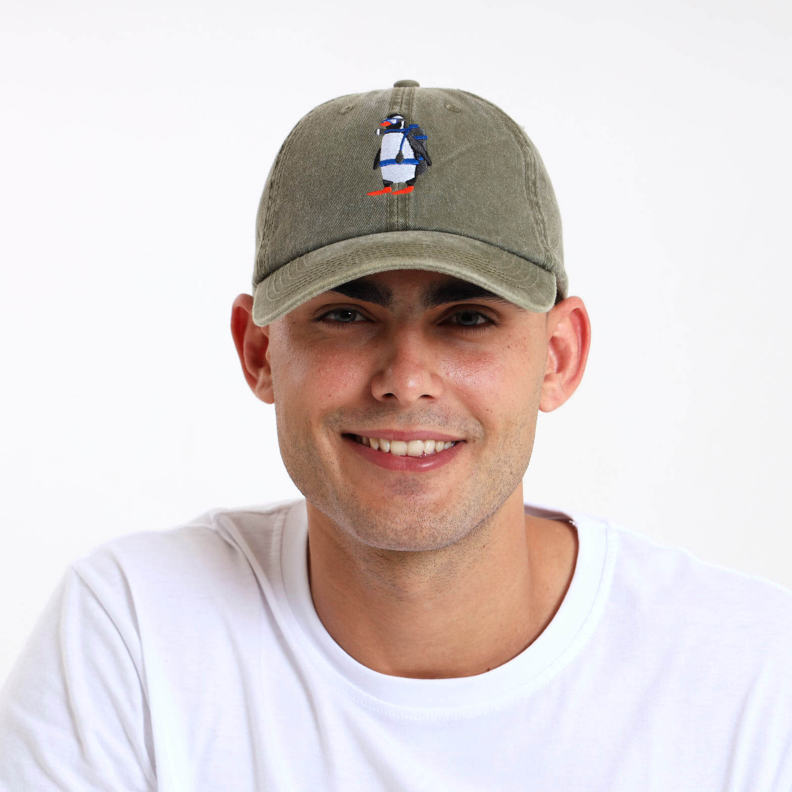 Man wearing an army green cap with a penguin design on the front panel.