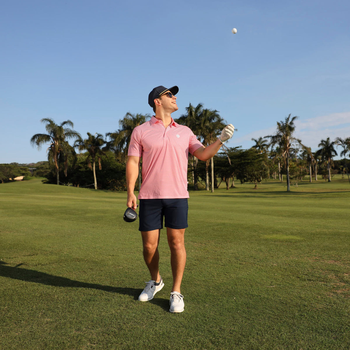 Man wearing a red striped Breazies golf shirt and navy golf shorts.