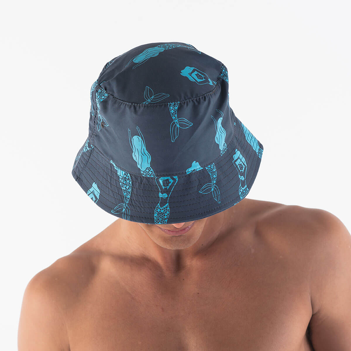 A man wearing a steel blue bucket hat with a design featuring blue mermaids all over.
