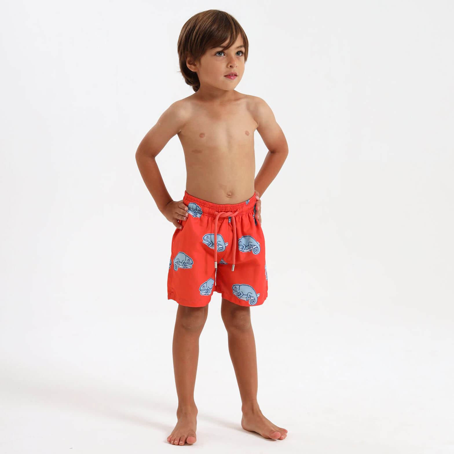 Boy wearing orange swim shorts with blue chameleon design