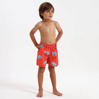 Boy wearing orange swim shorts with blue chameleon design