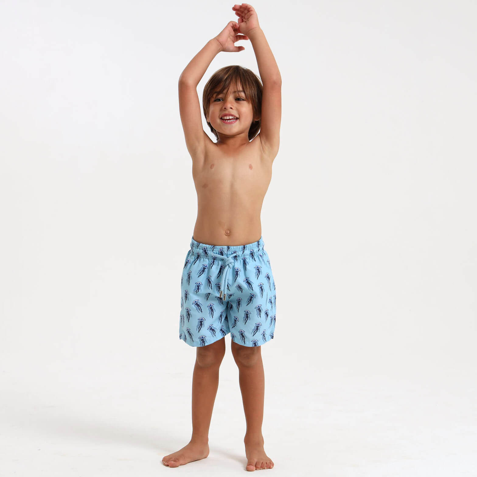 A kid wearing cool blue swim shorts with a jellyfish design on them.