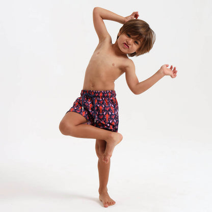 Boy wearing navy swim shorts with an  orange lobster design.