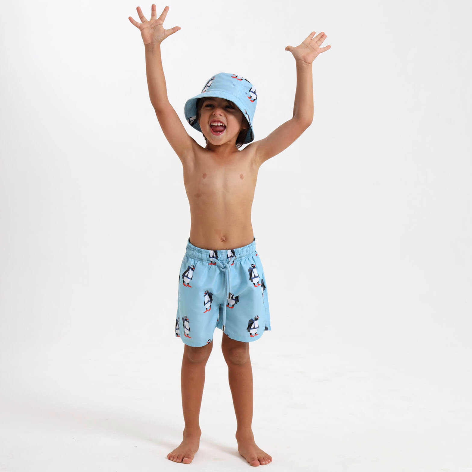 Child wearing light blue swim shorts with an elasticated waist and a scuba diving penguin design.