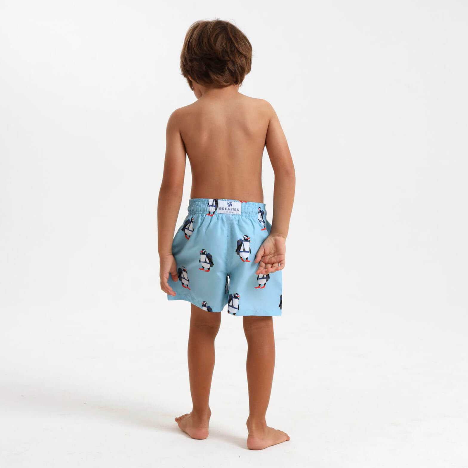 Child wearing a pair of Breazies blue penguin swim shorts.