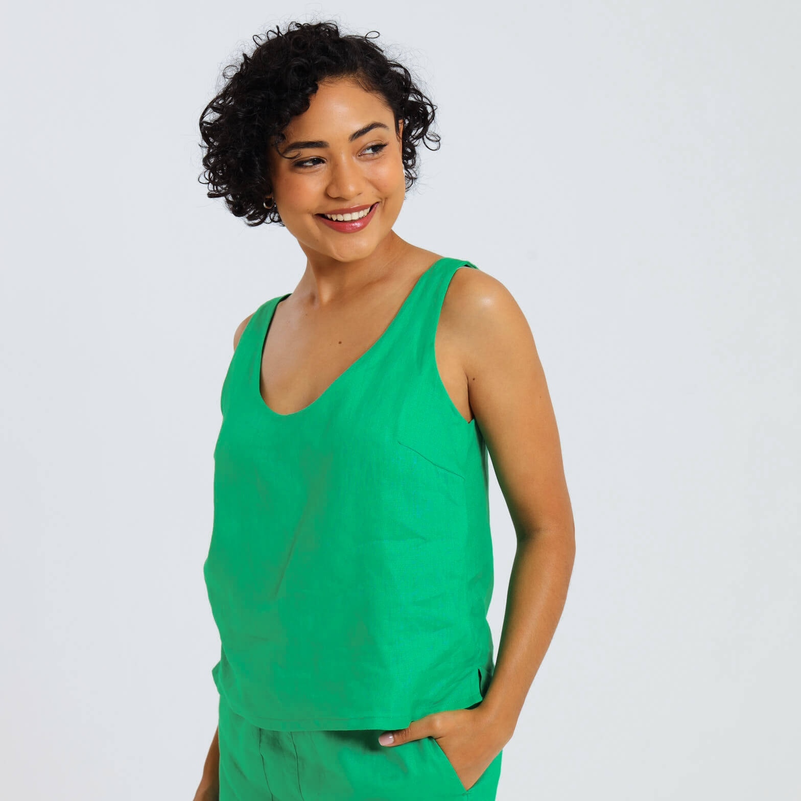 A woman wearing a green sleeveless linen cami top with a round neck.