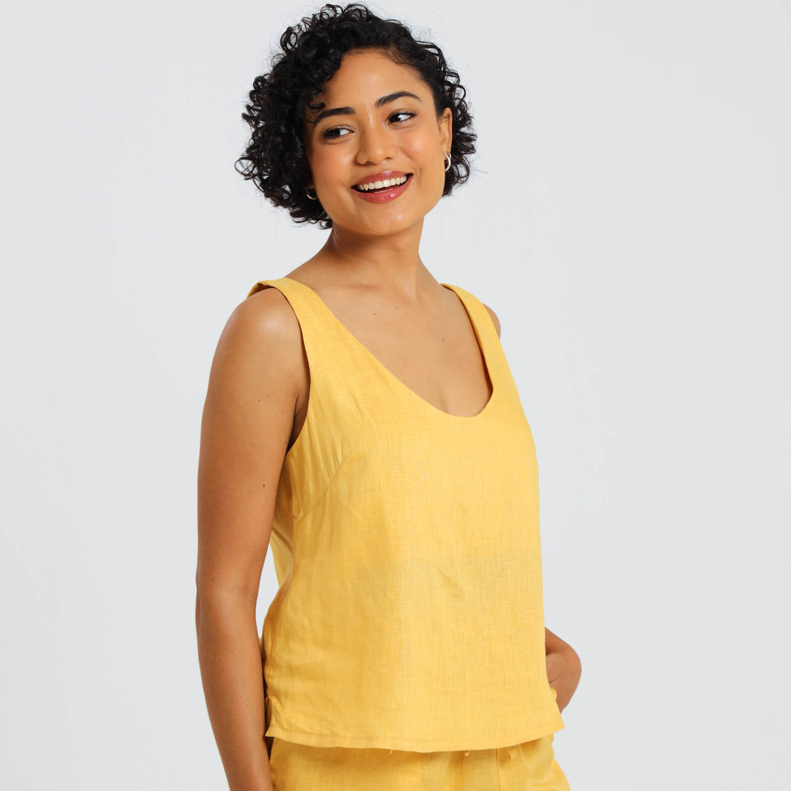 Female model wearing a mustard yellow linen cami top with matching linen shorts.