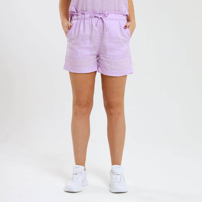 Woman wearing lilac linen shots with side pockets and matching draw string being paired with white sneakers.