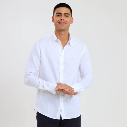 A man wearing a white long sleeve linen shirt paired with dark trousers.