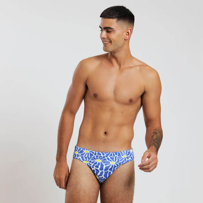 A man wearing a blue and yellow floral-patterned swim brief.