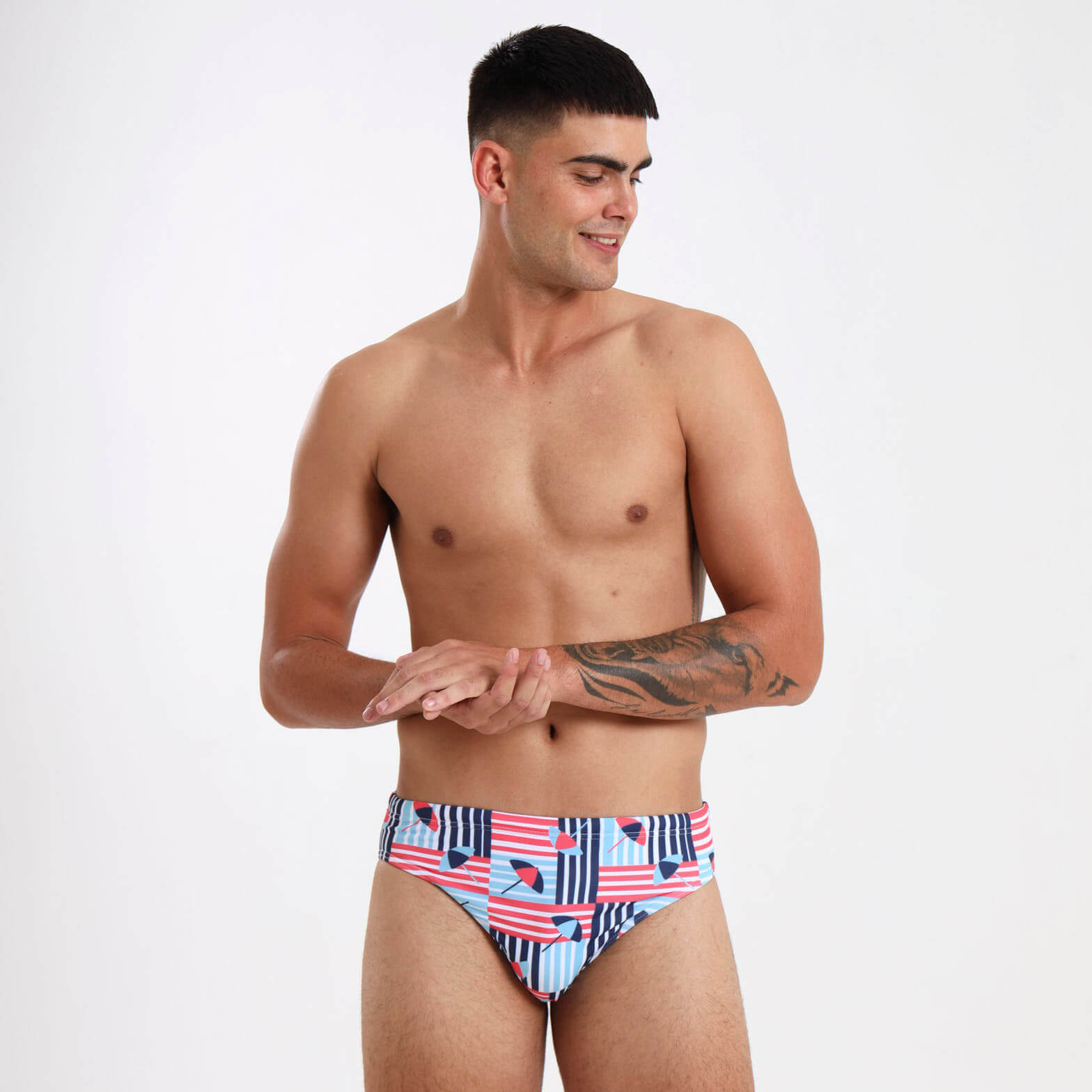 Man wearing striped swimming briefs featuring  a blue and red umbrella design.