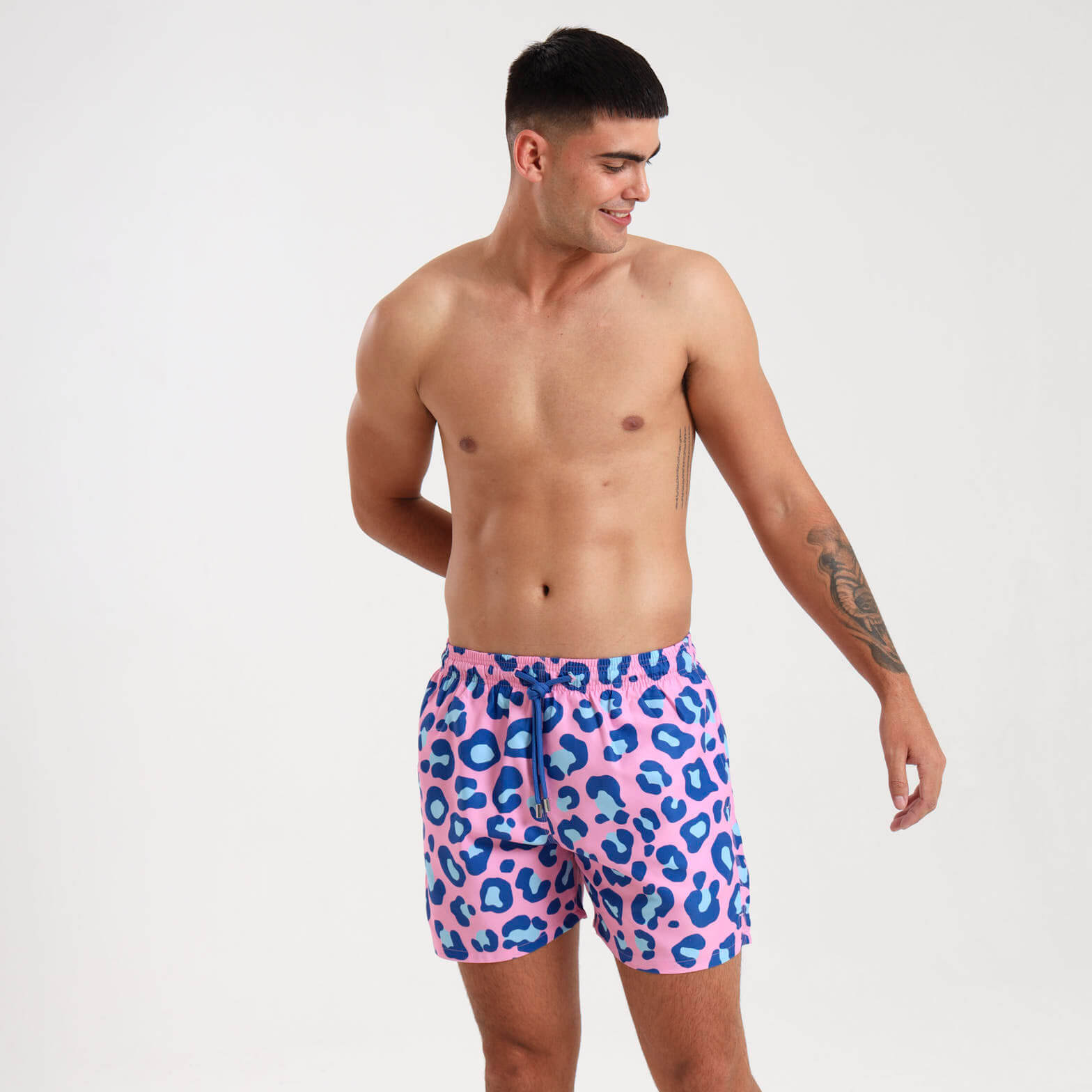 Man wearing pink and blue swim shorts with a leopard print pattern