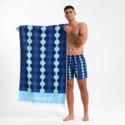 Man holding a blue geometric patterned towel with 'Breazies' branding.