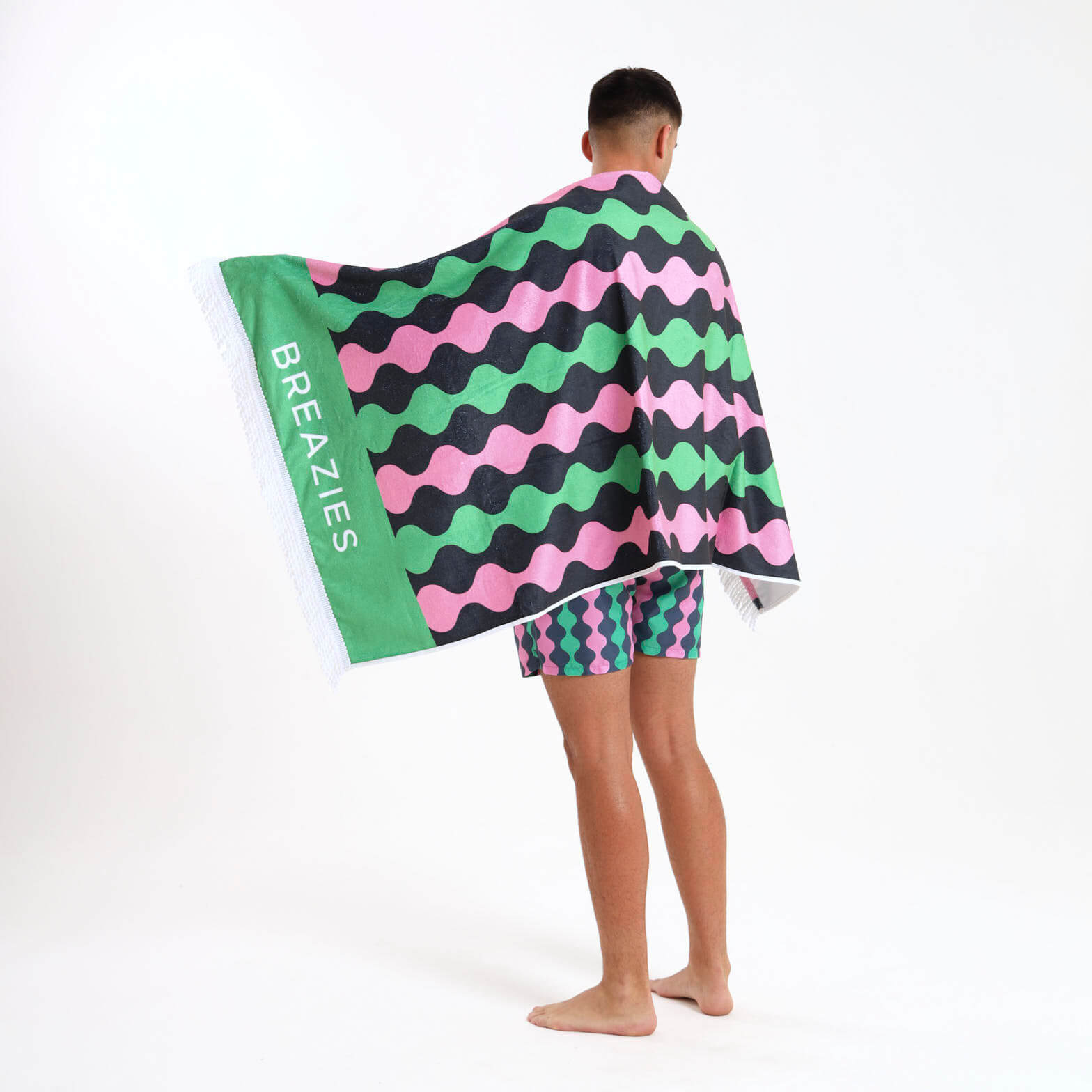 Person wearing a colorful towel with wavy green and pink pattern and 'BREAZIES' branding.