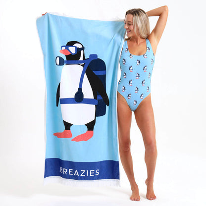 Woman holding a blue towel and wearing a matching swimming costumer featuring a scuba diving penguin.