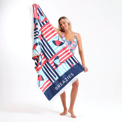 Woman holding a colourfully striped beach towel with 'Breazies' branding.