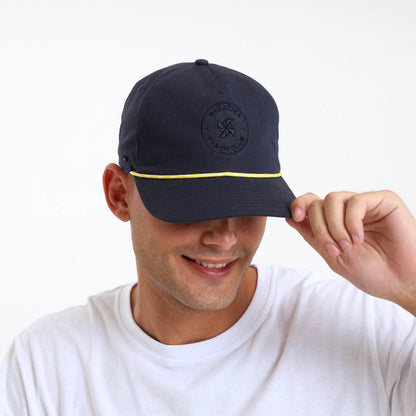 Man wearing a navy blue cap with embroidered branding and a yellow string
