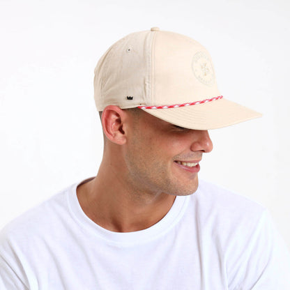 Man wearing a beige cap with a self colour Breazies Beach Club logo embroidered on the front panel.