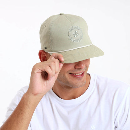 Man wearing a pistachio coloured cap with a same colour logo on the front panel.