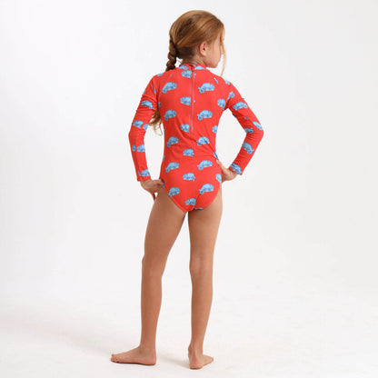 Young girl wearing a long sleeve swimming costume with an orange and blue chameleon print.