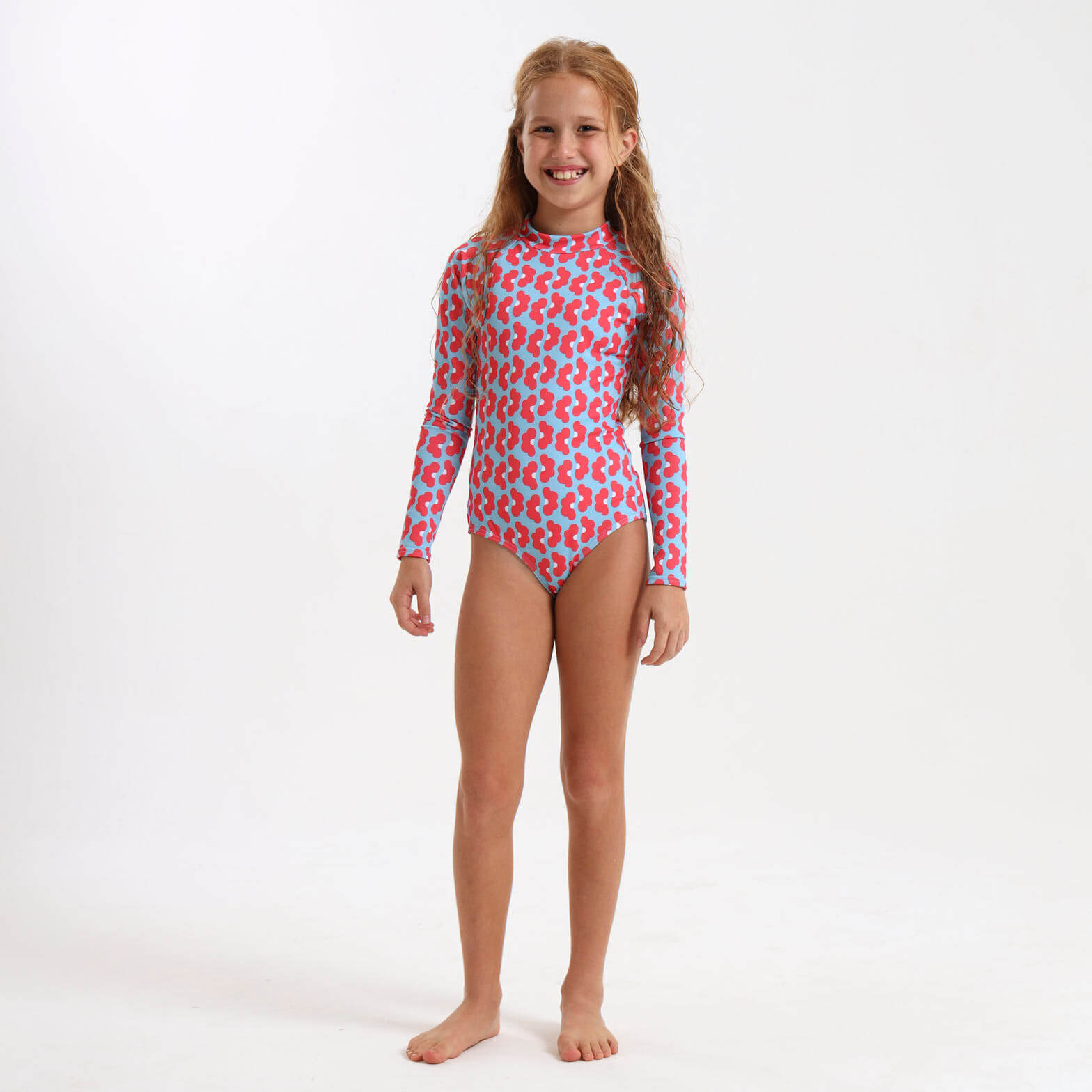 Girl wearing a long sleeve swimsuit featuring a blue and coral daisy print.