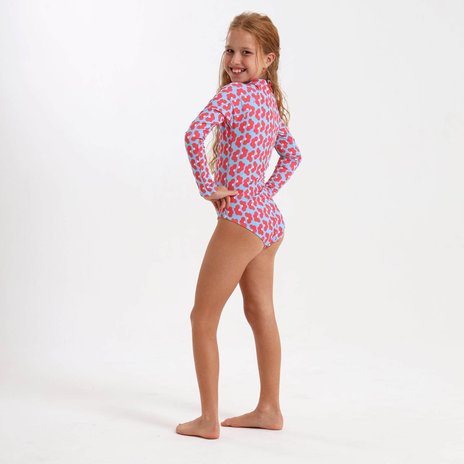 Girl wearing a long sleeve swimming costume with a coral and blue daisy print.