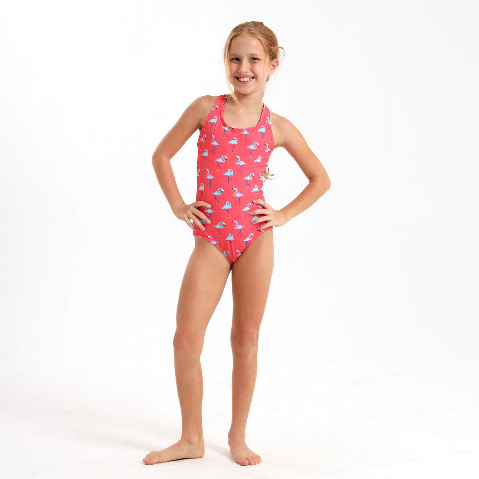 Girl wearing a coral one piece swimsuit with a blue flamingo print.