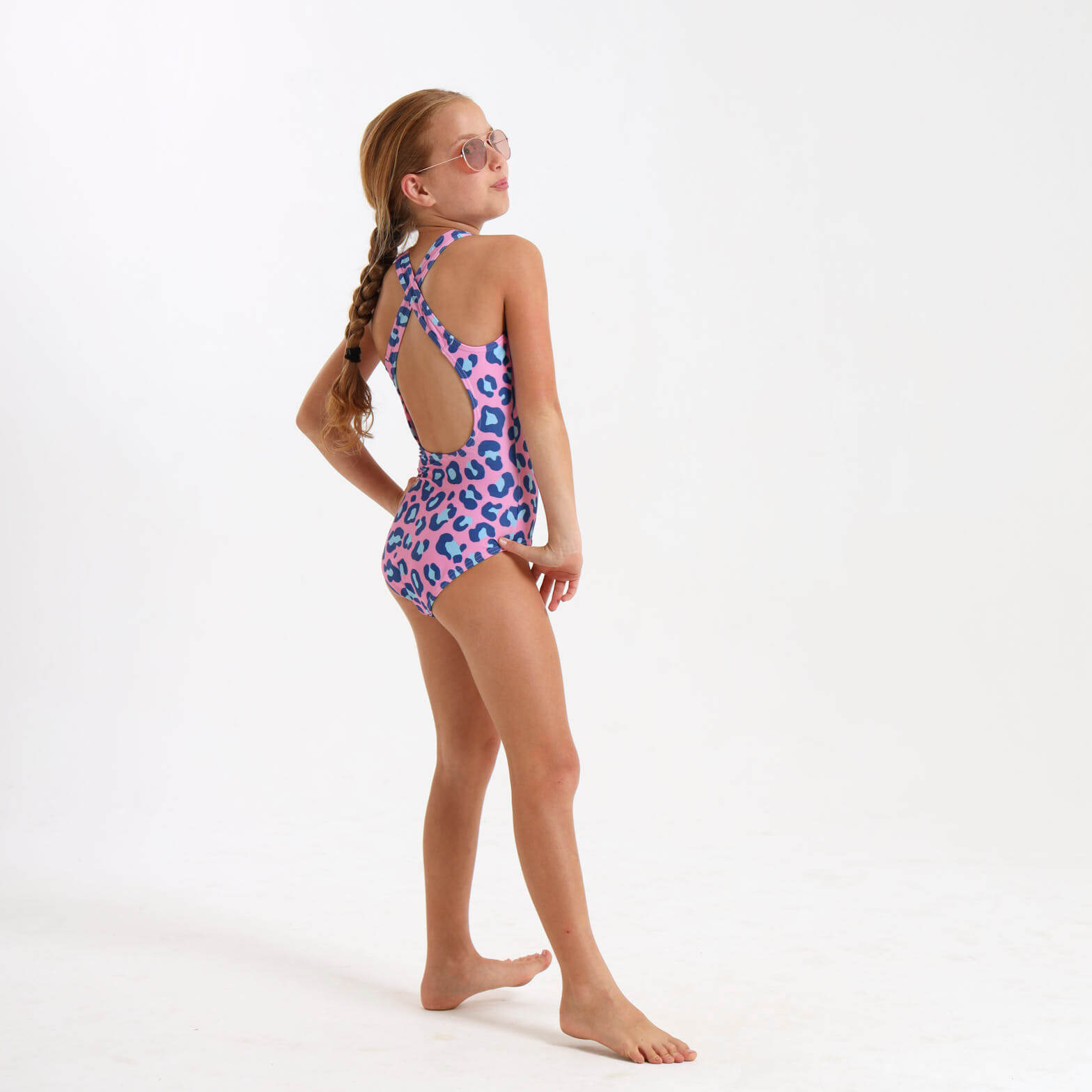Girl wearing a leopard print swimsuit with a cross over strap on the back.