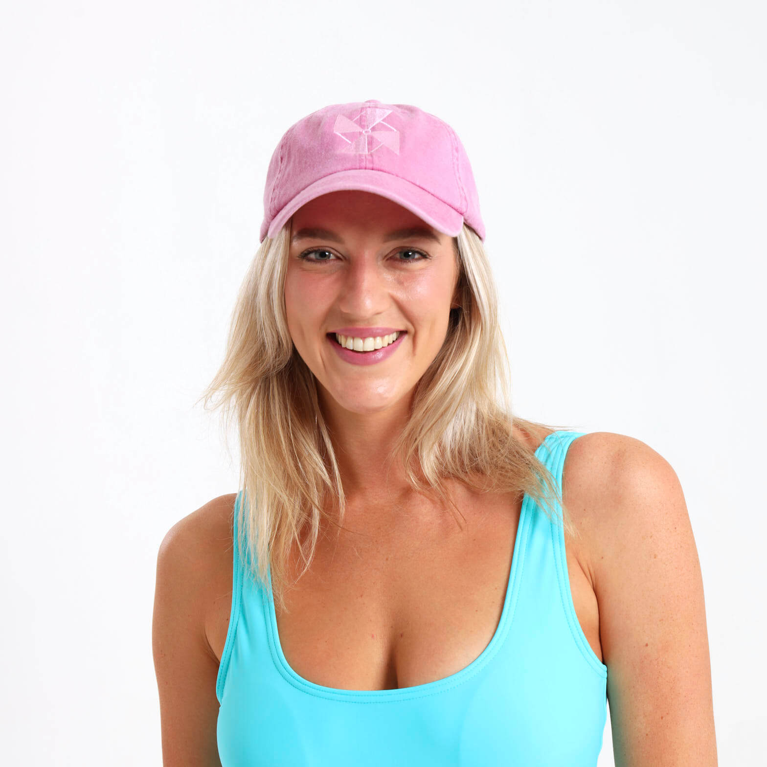 Woman wearing a pink cap with a Breazies logo visible on the front panel. She is also wearing a turquoise tank top .