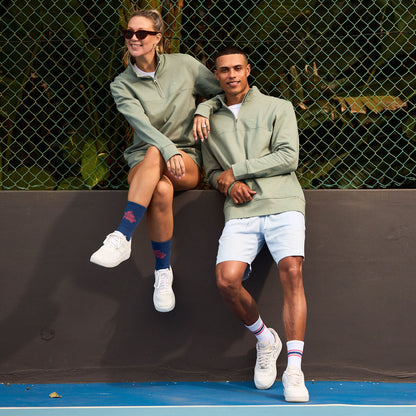 Two people wearing unisex cotton quarter zip sweaters by Breazies. Featuring a self coloured embroidered logo.