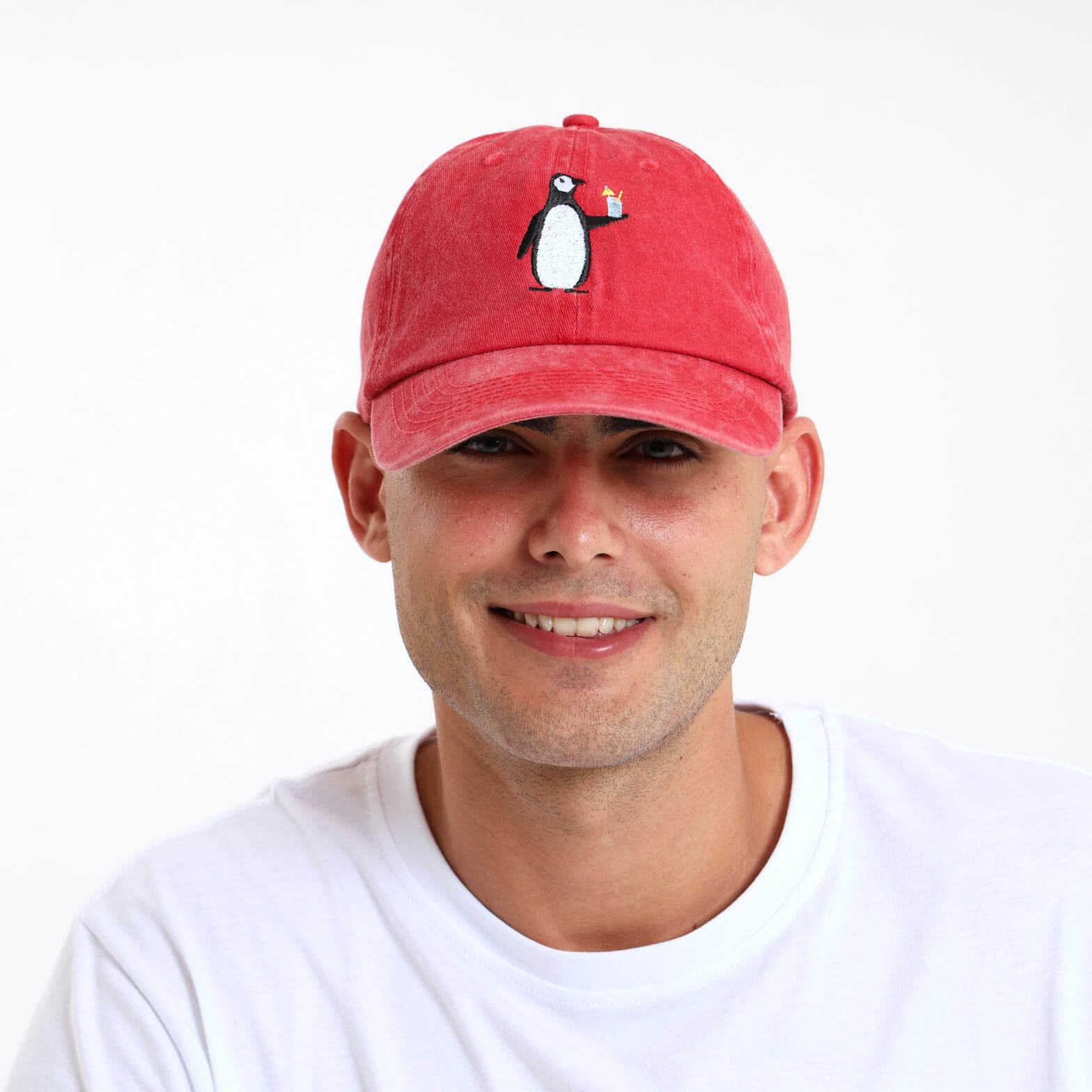 Man wearing a red cap with a penguin design on the front.